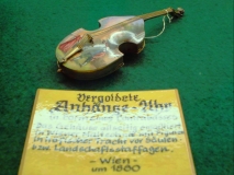 Uhrenmuseum Wuppertal vergoldete Anhänge-Uhr (Armbanduhr) in Form einer historischen Violine bemalter Decke Schild in Schauvitrine : … Wien 1880 © noten-apitz.de; Bildquelle: Musikverlag Apitz